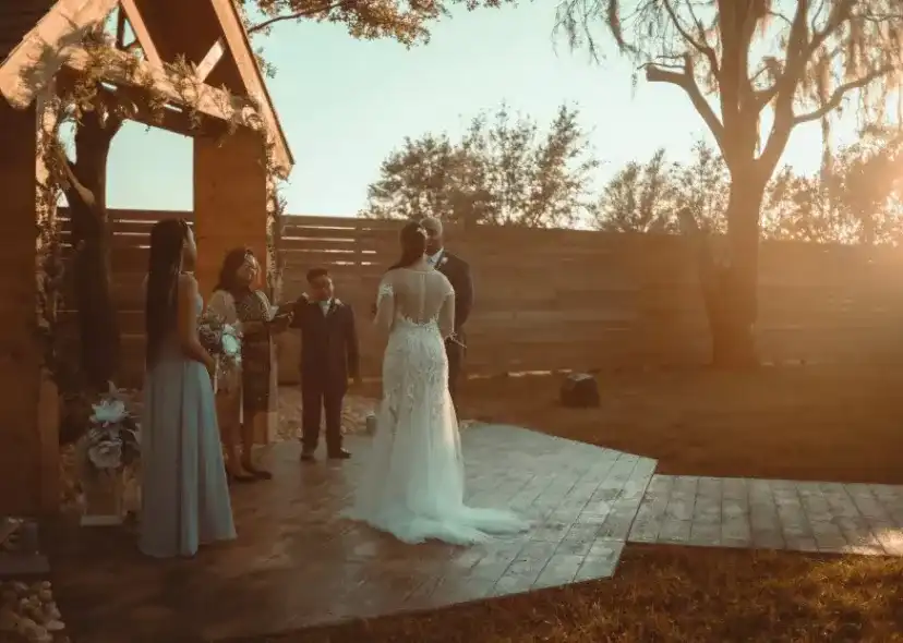 An outdoor gazebo wedding ceremony at golden hour with an officiant, a bridesmaid and a ring bearer