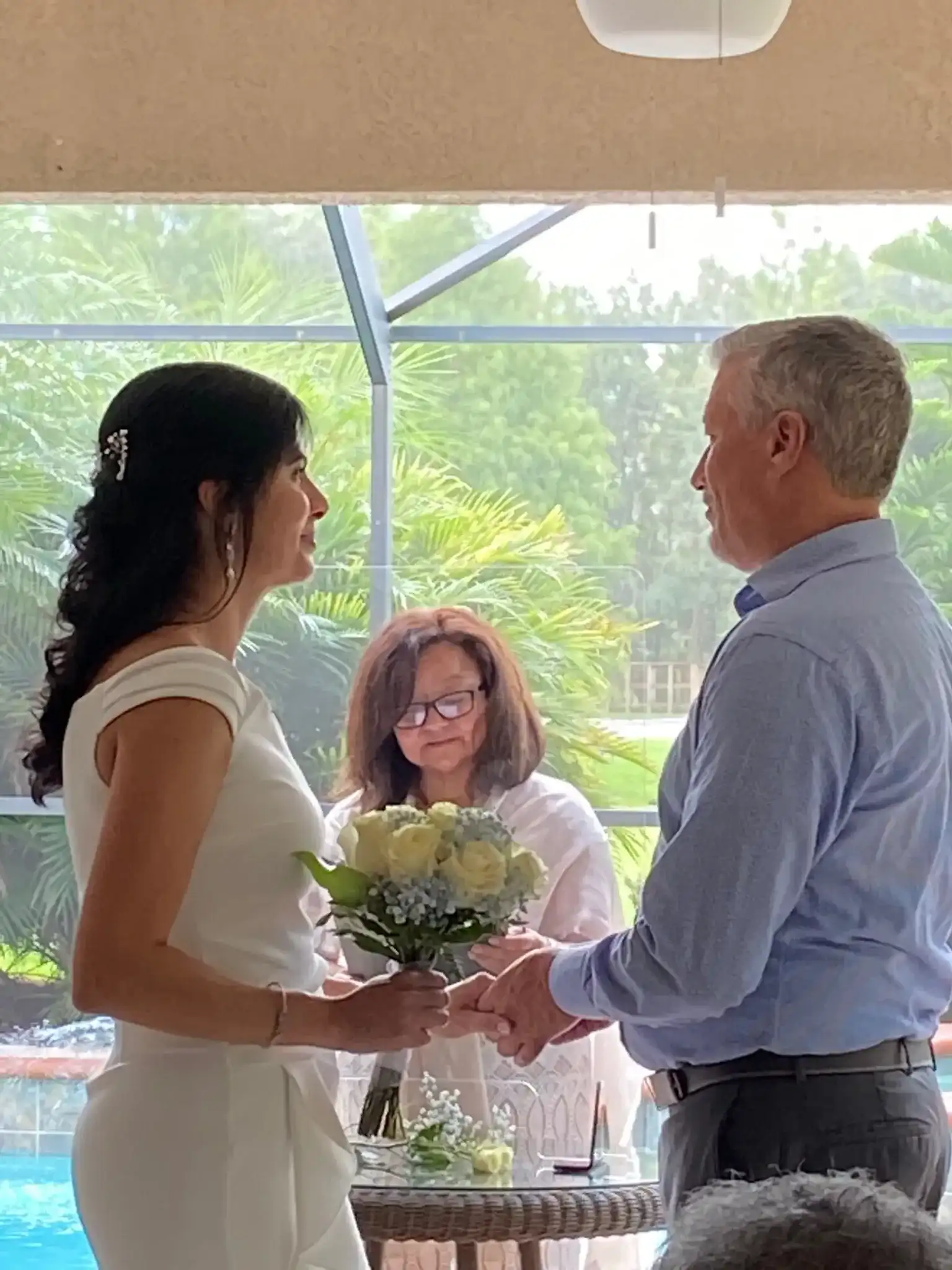 Rocío officiating a ring and vow exchange in a screened lanai with the couple holding hands